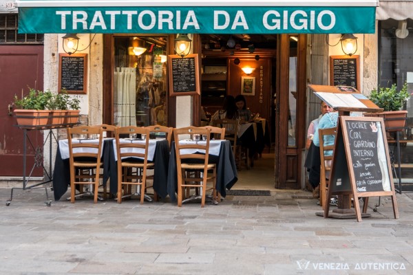 Entrance to the Trattoria da Gigio on the Strada Nuova in Venice, showing tables and chairs both on the outisde and on the inside of the restaurant. Small picture.