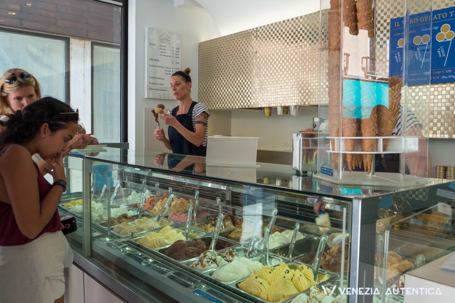 Young woman deciding which gelato flavour to pick in Venice, Italy